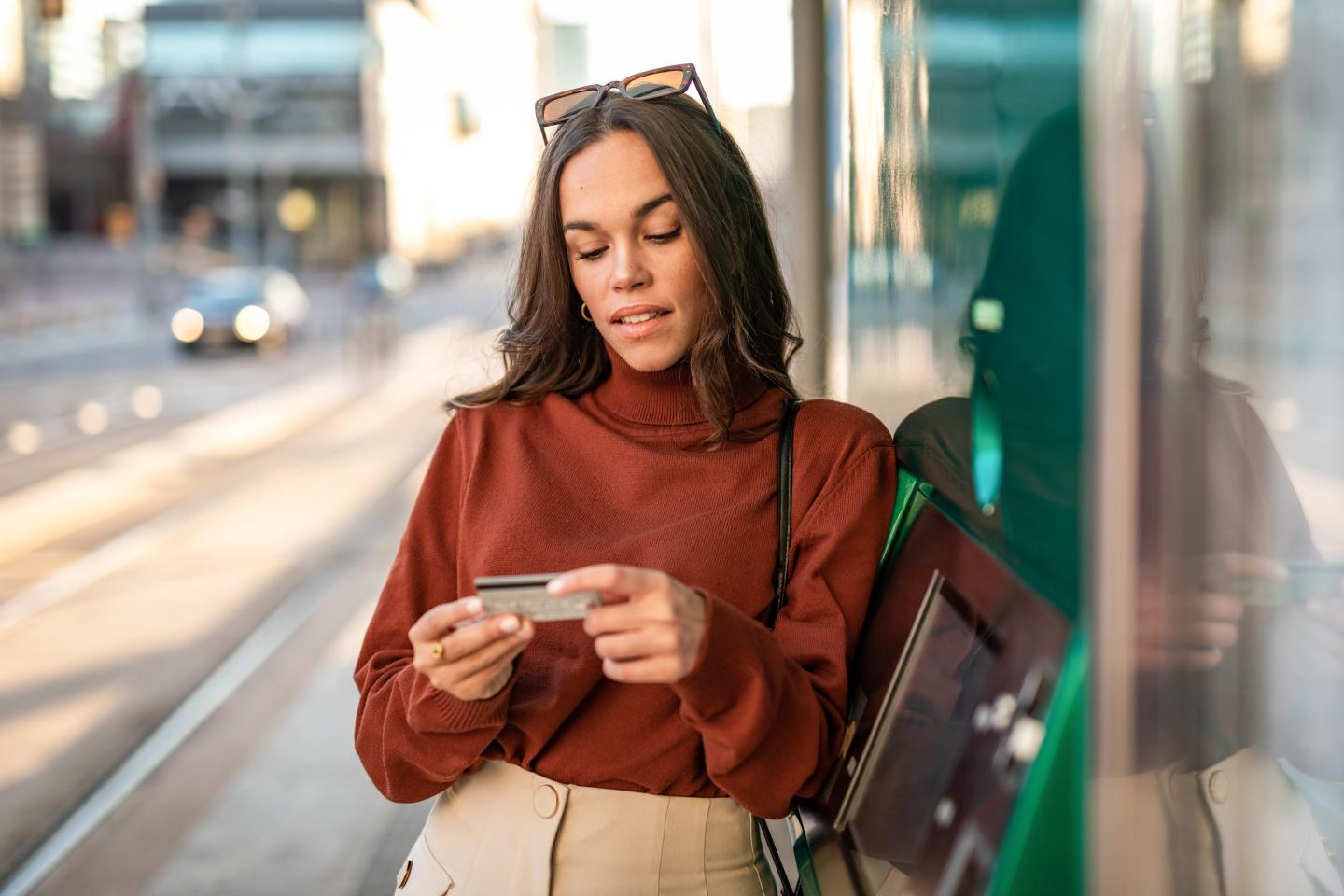 Photo of a young woman using an ATM to withdraw money for shopping