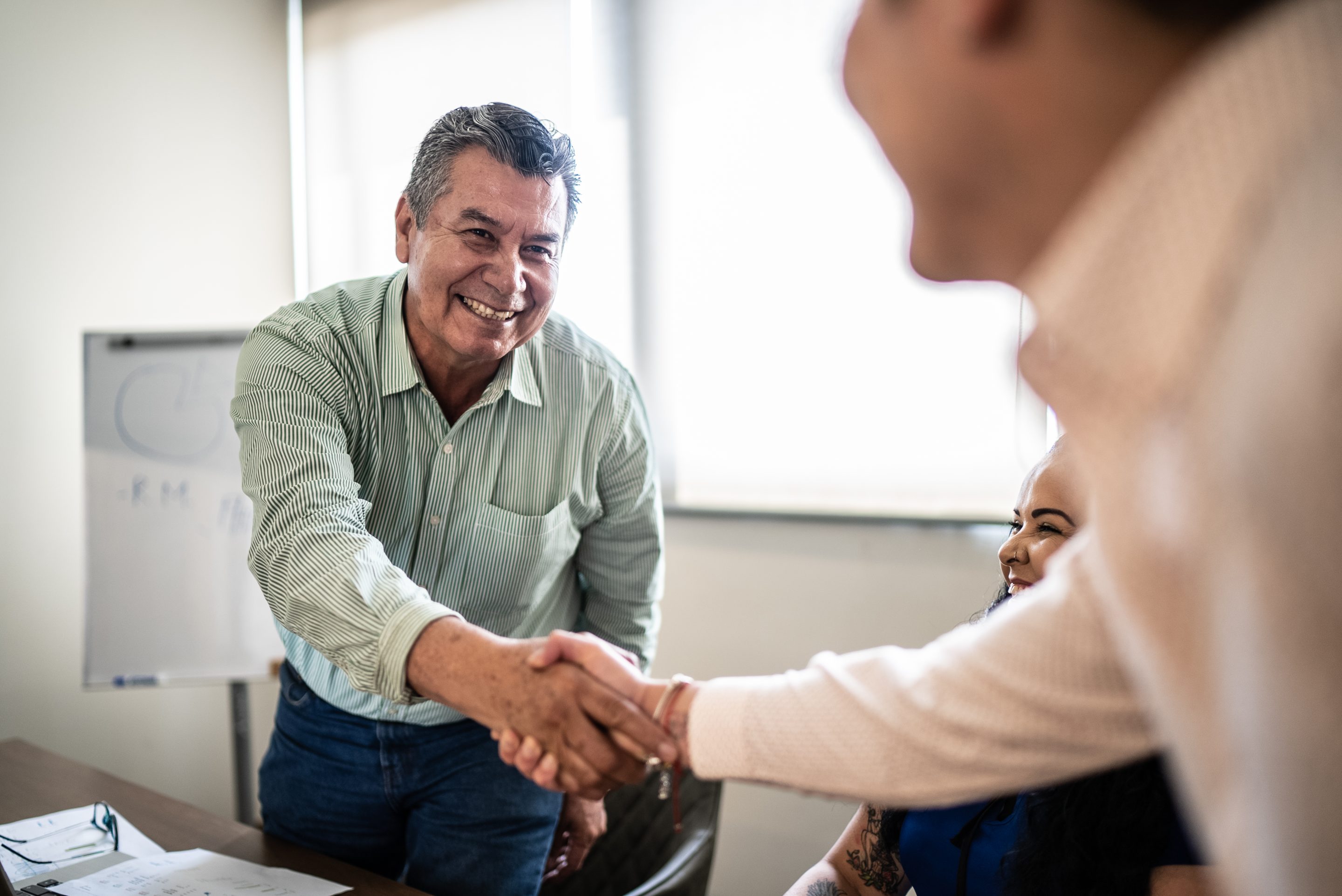 Senior worker shaking hands with worker in a training class