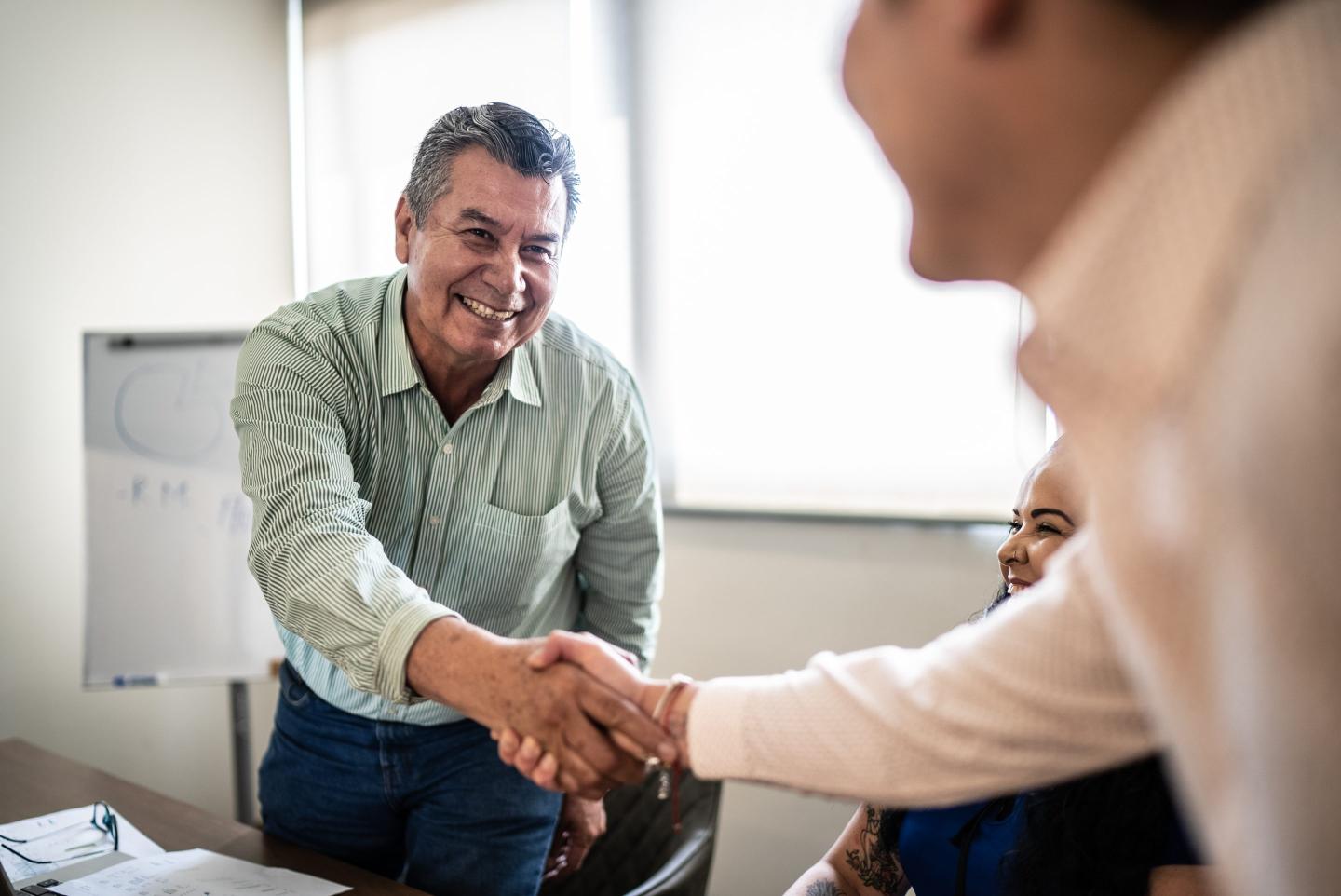 Senior worker shaking hands with worker in a training class