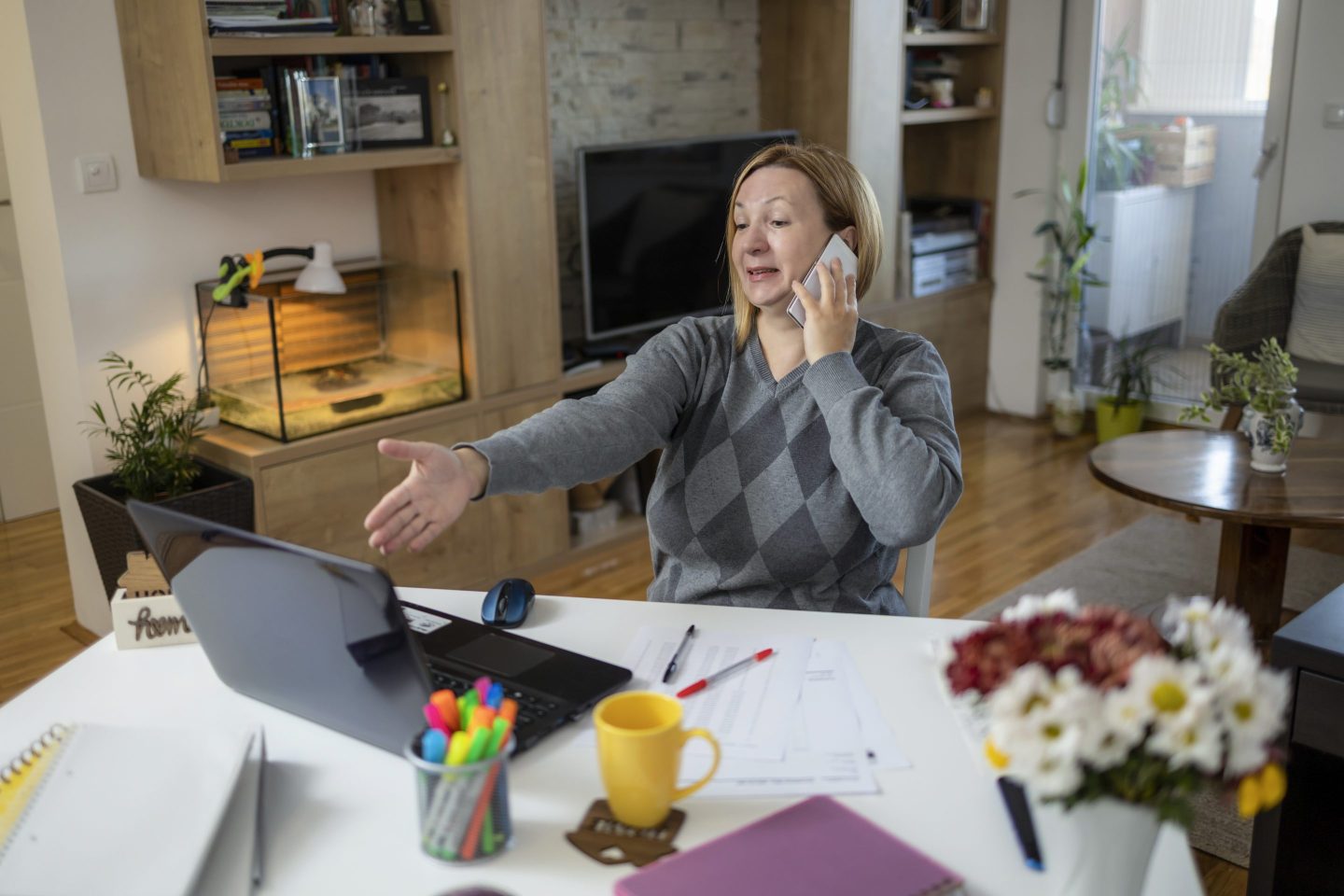 Shot of an adult businesswoman sitting alone in her home office and talking on her cellphone