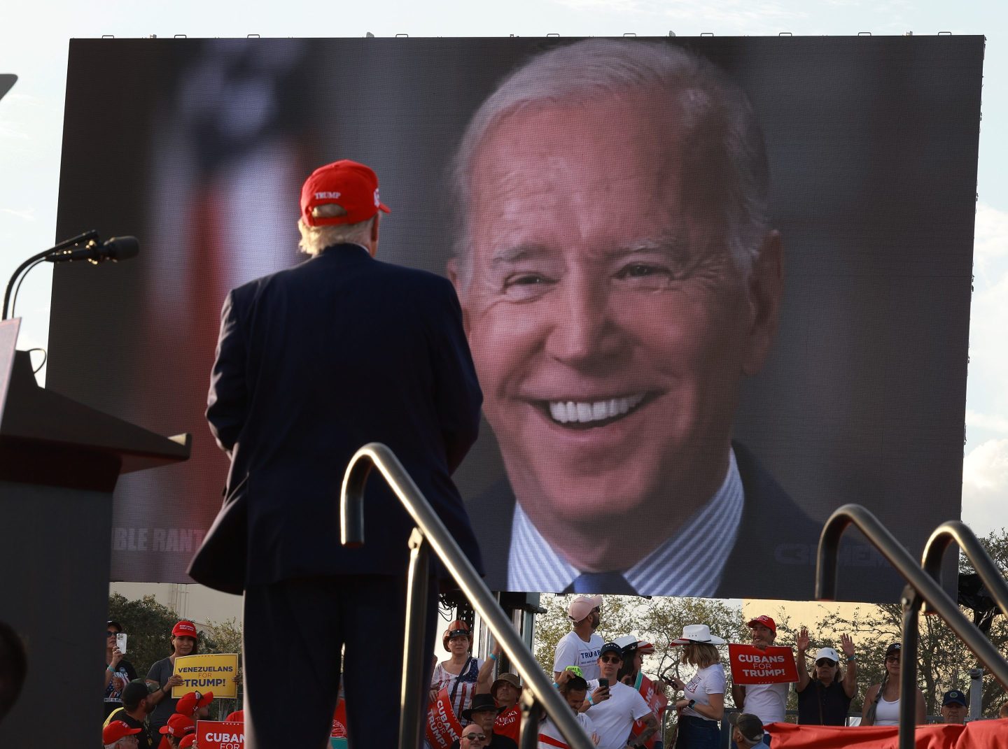 Former U.S. President Donald Trump watches a video of President Joe Biden playing during a rally