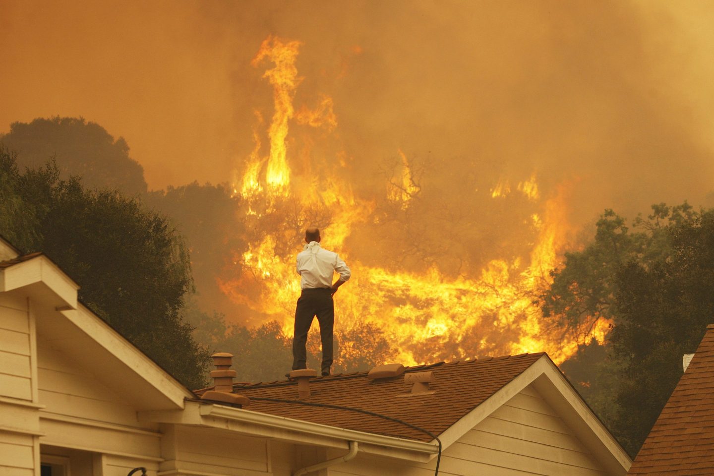 A man stands on a rooftop, looking at approaching flames during the Springs fire on May 3, 2013 near Camarillo, Calif.