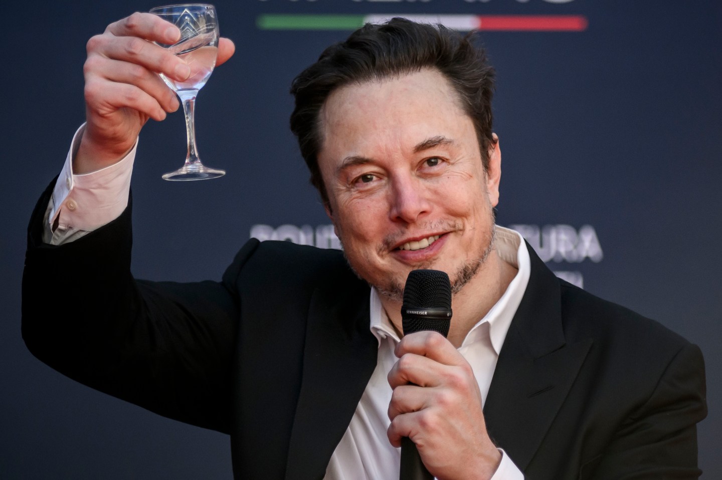Elon Musk holding up a glass of champagne
