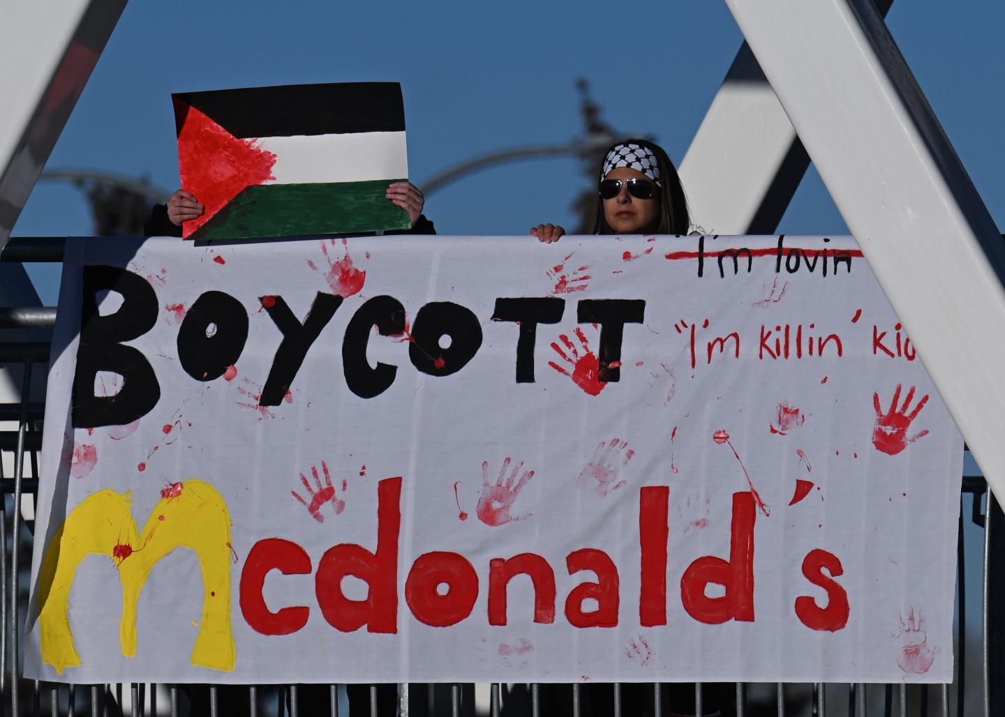 Members of the local Palestinian diaspora hold a banner that reads 'Boycott McDonald's' during the 'Action Boxing Day' protest on the WEM pedestrian bridge leading to the West Edmonton Mall, renowned as North America's Largest Shopping Mall