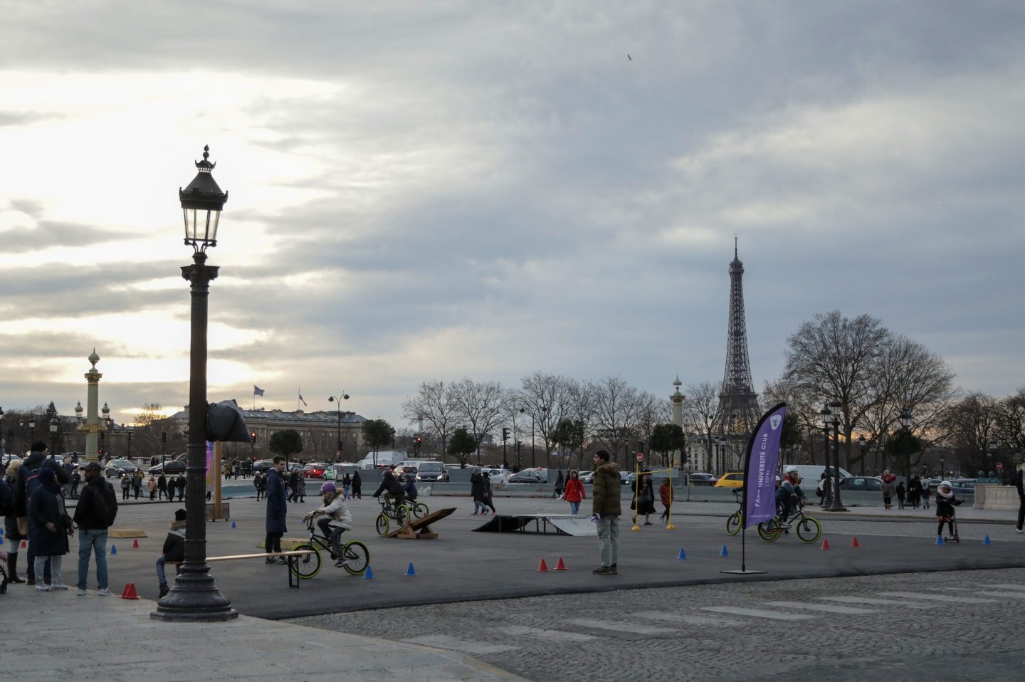 a scattered crowd seen in an open area with the eiffel tower at the back