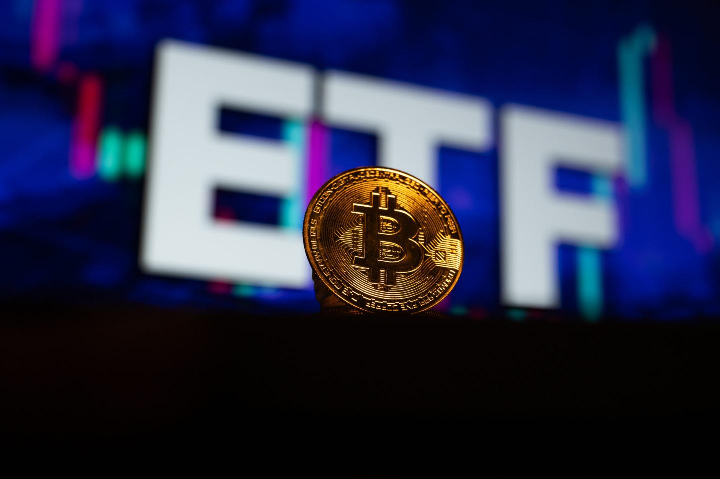 'Bitcoin' coin is displayed in front of a computer screen displaying 'EFT'.
