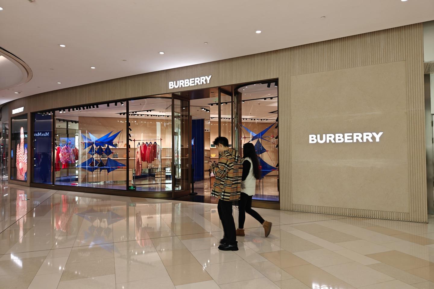 people walking by a Burberry store
