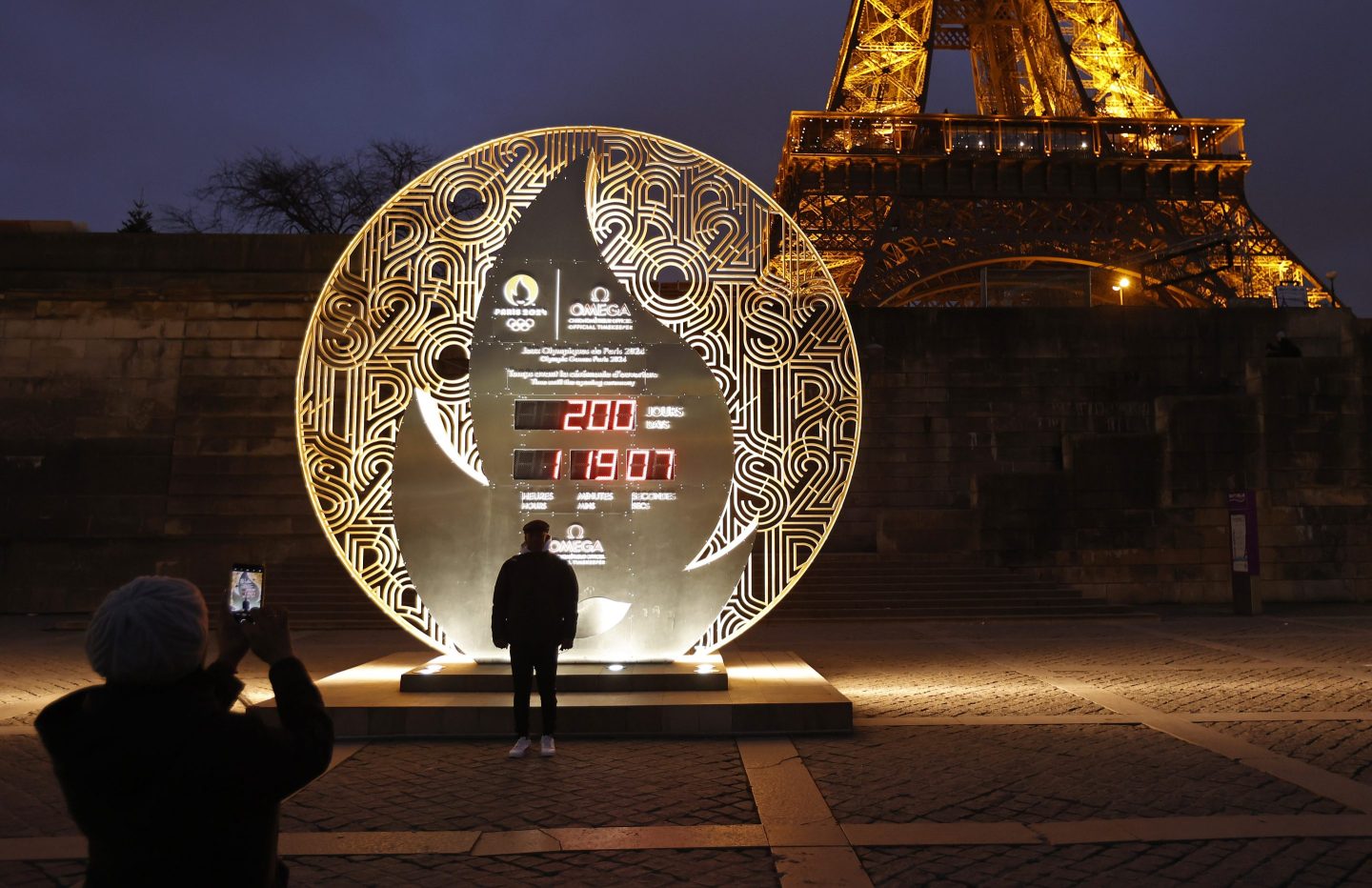 person standing in front of a countdown clock in front of Paris's Eiffel Tower