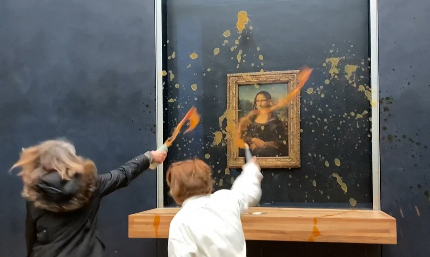 This image grab taken from AFPTV footage shows two activists hurling soup at Leonardo Da Vinci's "Mona Lisa" painting, at the Louvre museum in Paris on Sunday.
