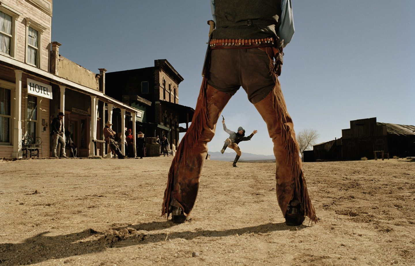 Photo illustration of a gunslinger's legs as he faces off in a showdown with another cowboy.