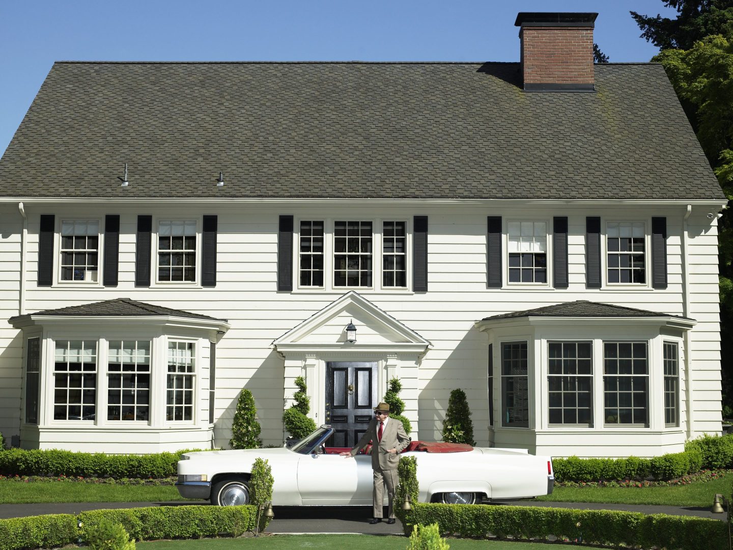 Senior man standing by convertible car outside house