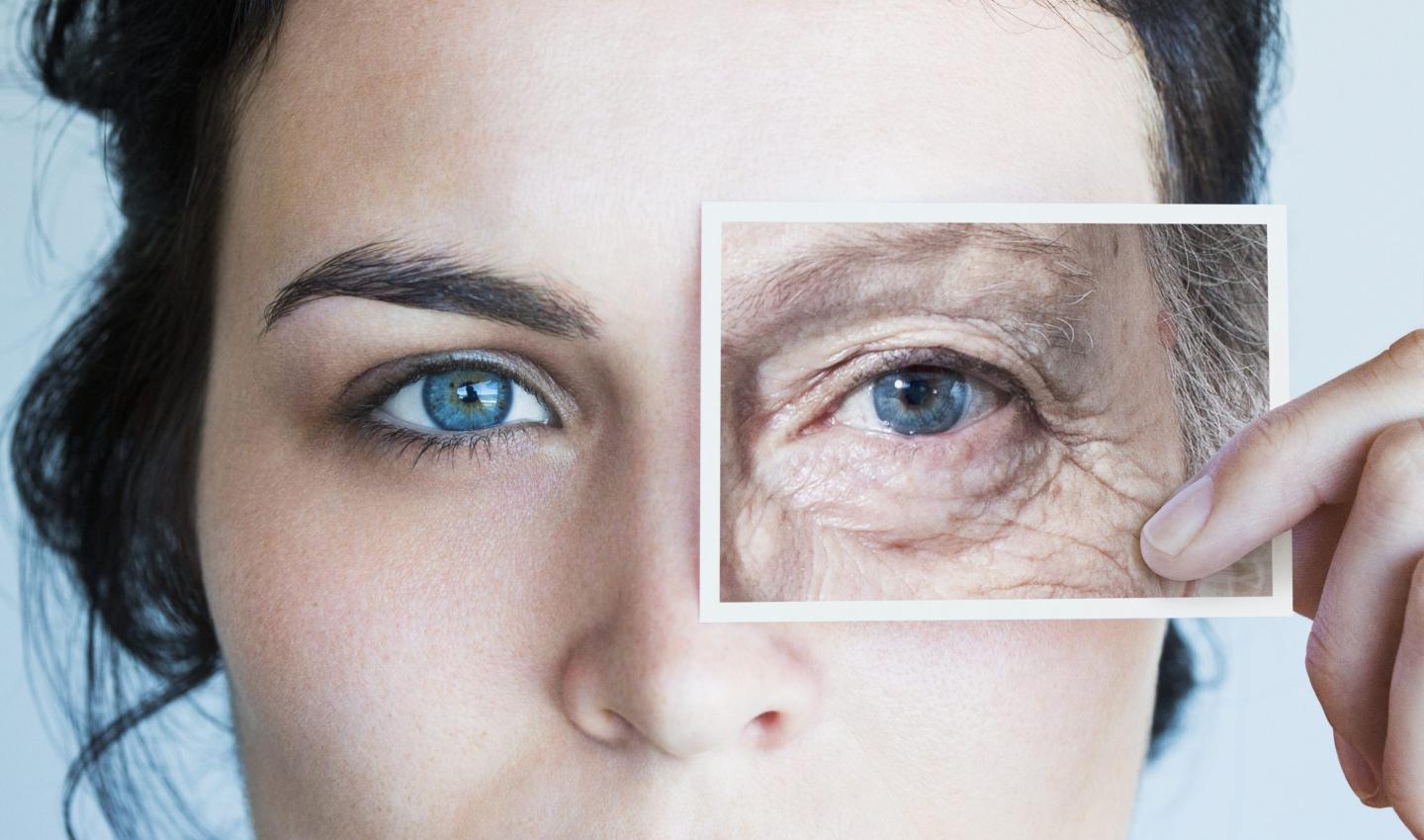 Young woman holding a photo in front of one of her eyes