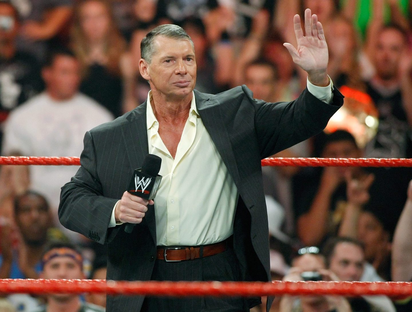 Vince McMahon in the wrestling ring holding a microphone
