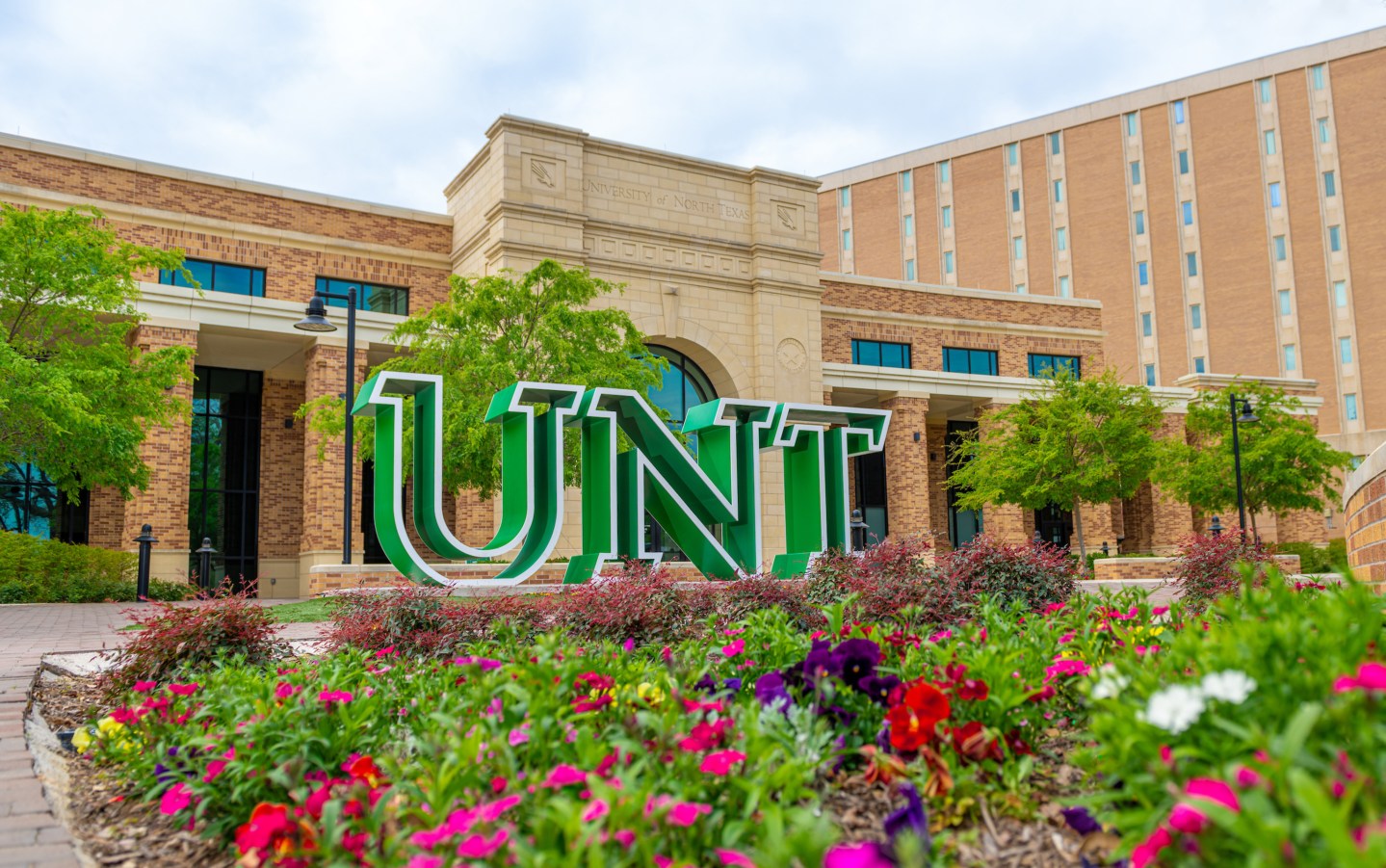 The green UNT logo is pictured in front of an academic building.