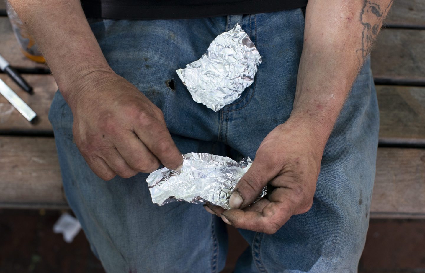 A man prepares to smoke fentanyl on a park bench in downtown Portland, Ore., on May 18, 2023.