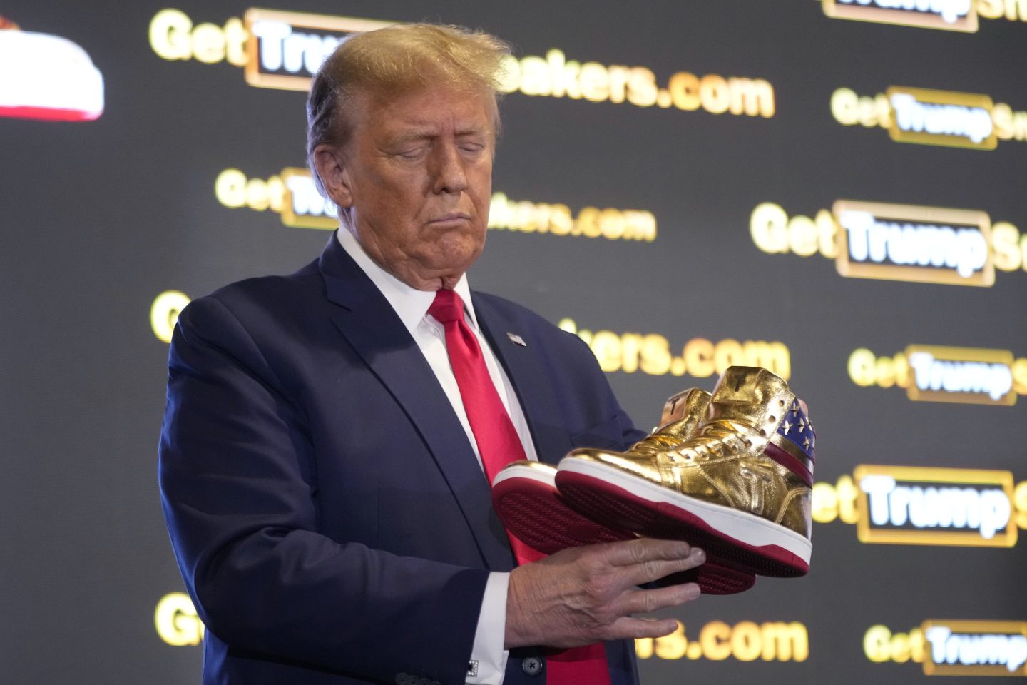 Republican presidential candidate former President Donald Trump holds gold Trump sneakers at Sneaker Con Philadelphia, an event popular among sneaker collectors, in Philadelphia, on Feb. 17, 2024.