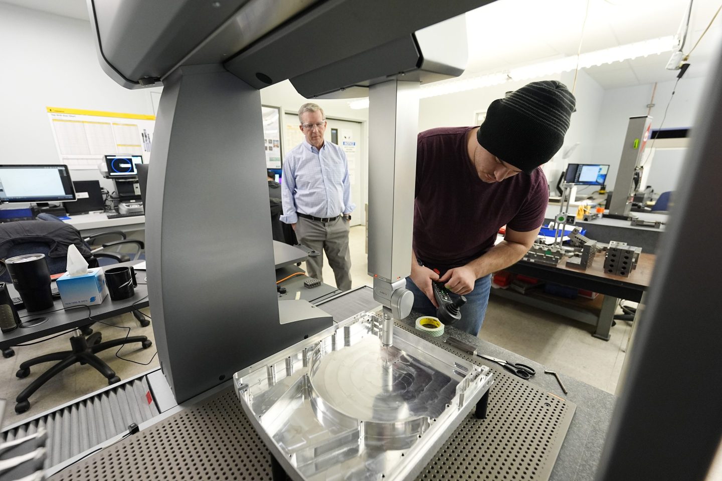 As Reata Engineering and Machine Works CEO Grady Cope looks on, a worker prepares a Hexagon machine to confirm that parts meet customers' standards, on Feb. 15, 2024, in Englewood, Colo.