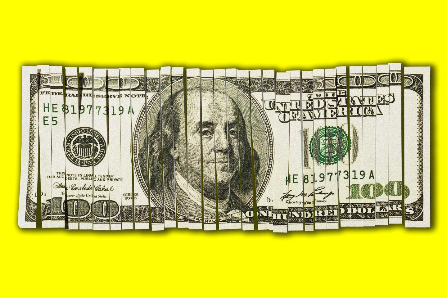 Shredded hundred dollar bill on yellow background.