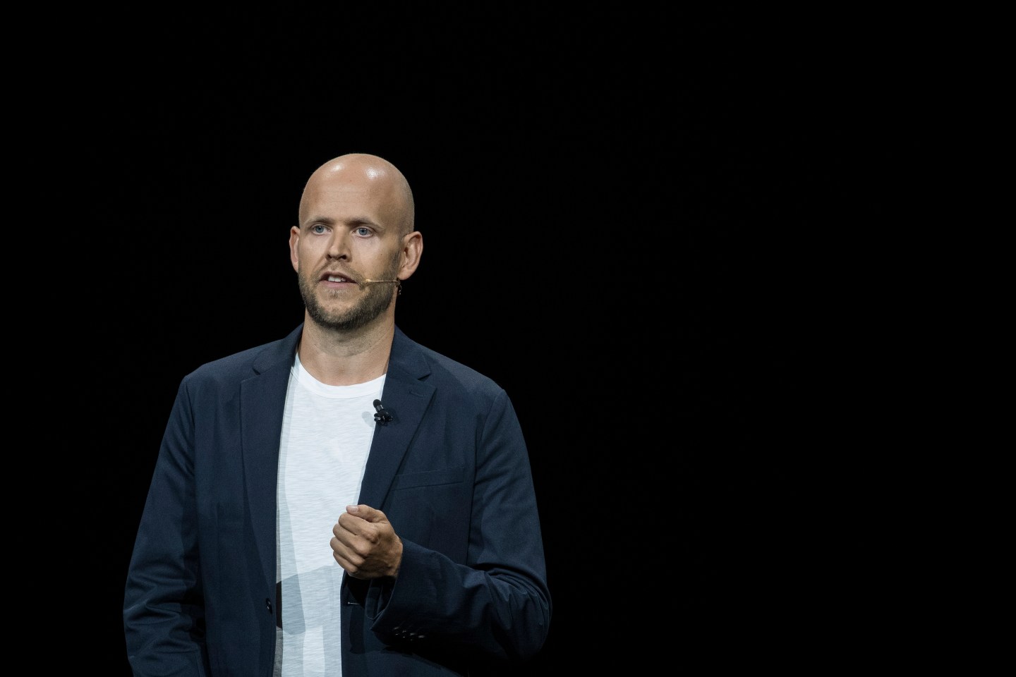 A bald middle-aged man talking in front of a black backdrop