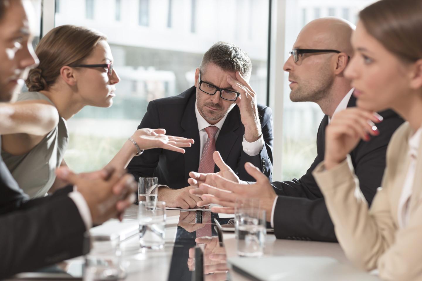 Workers speaking together with a boss looking overwhelmed. 