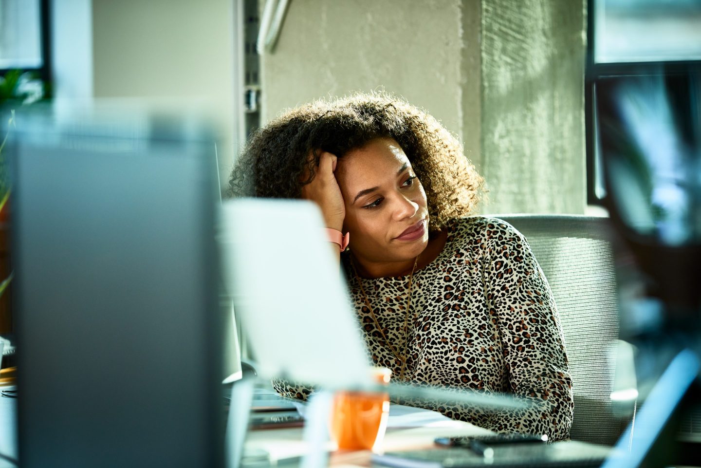 Portrait of a woman looking bored at her work desk.