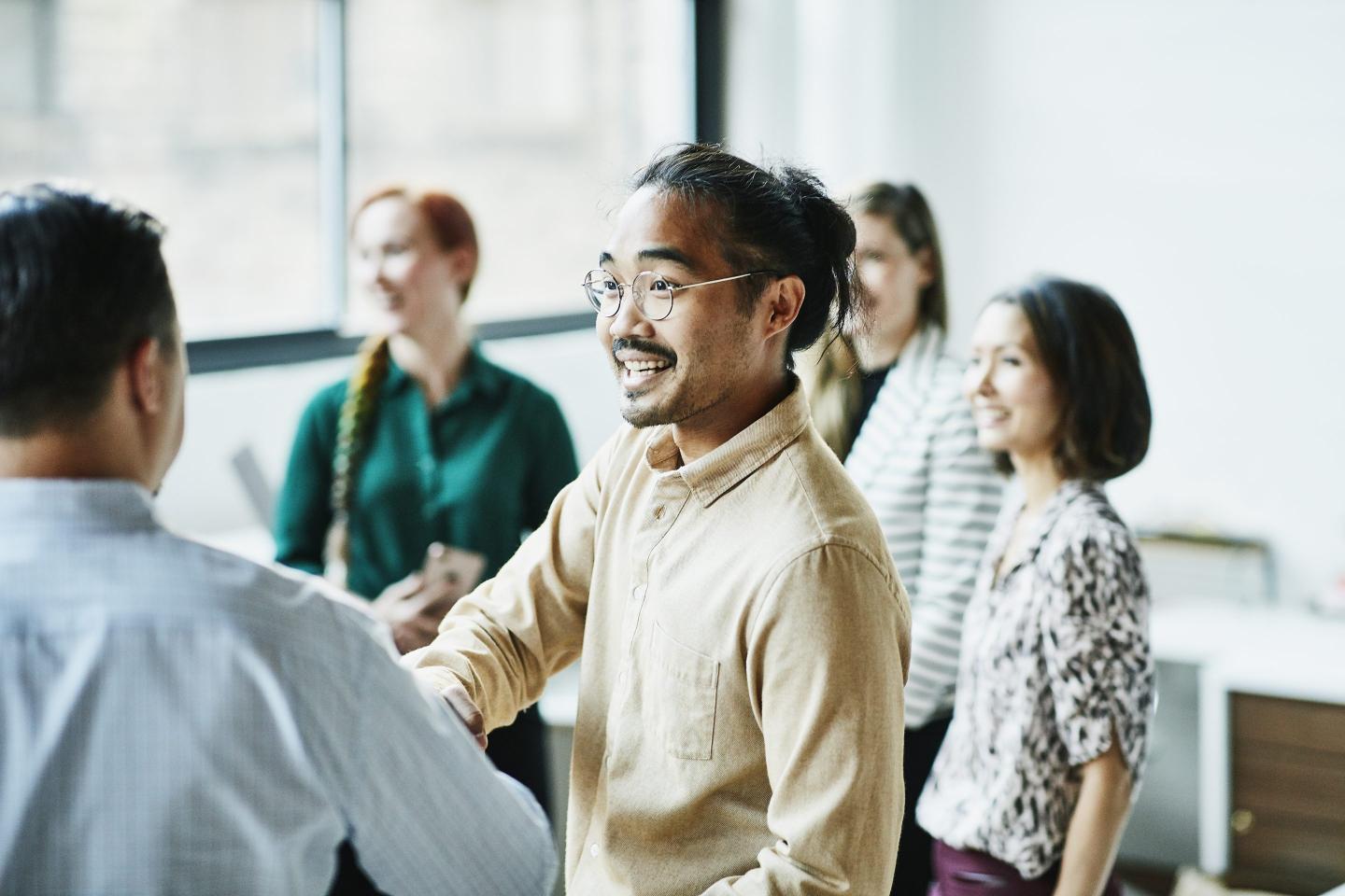 A man shakes hands with a colleague at a networking meeting.