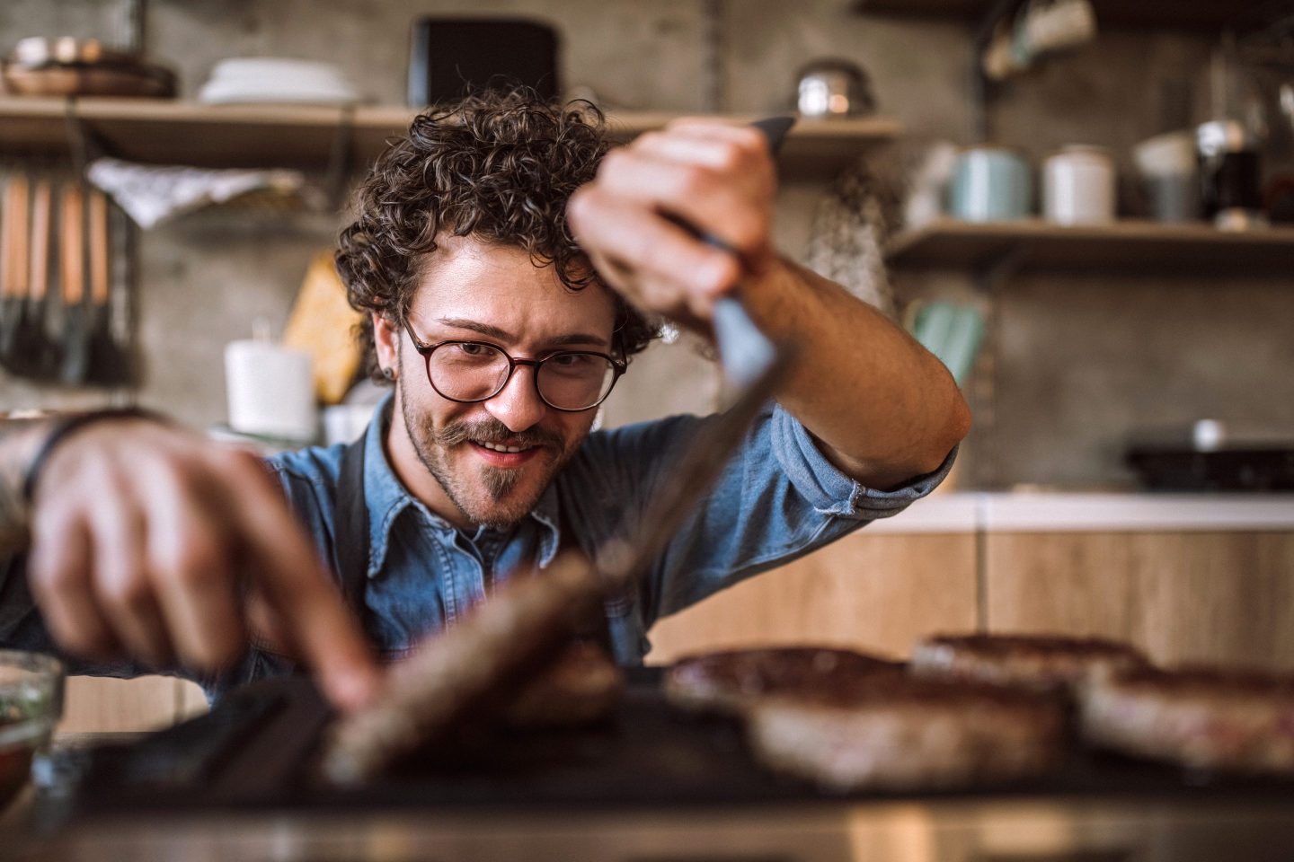 Hipster man turns a burger on a grill