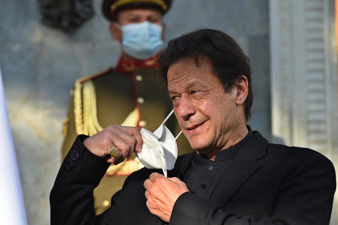 Former Pakistan Prime Minister Imran Khan removing a face mask