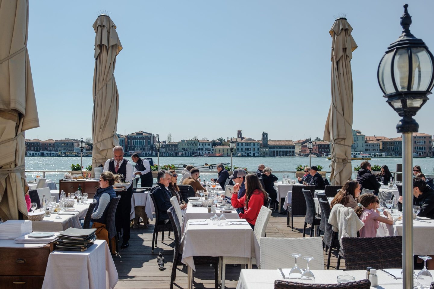 Tourists are seen eating and drinking at an outdoors terrace
