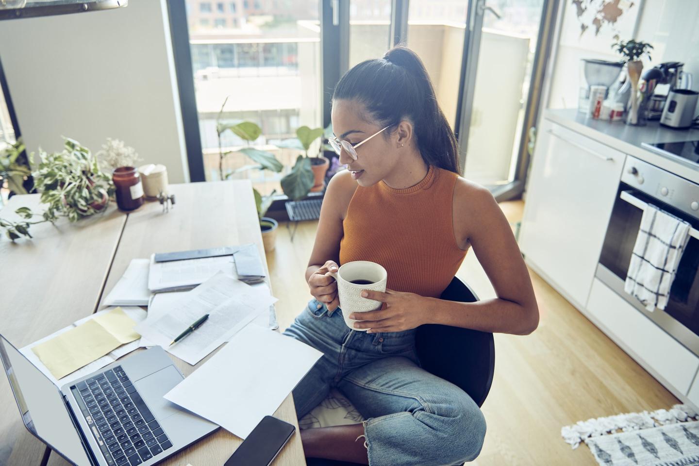 Woman using her computer and looking at various paper bills and statements