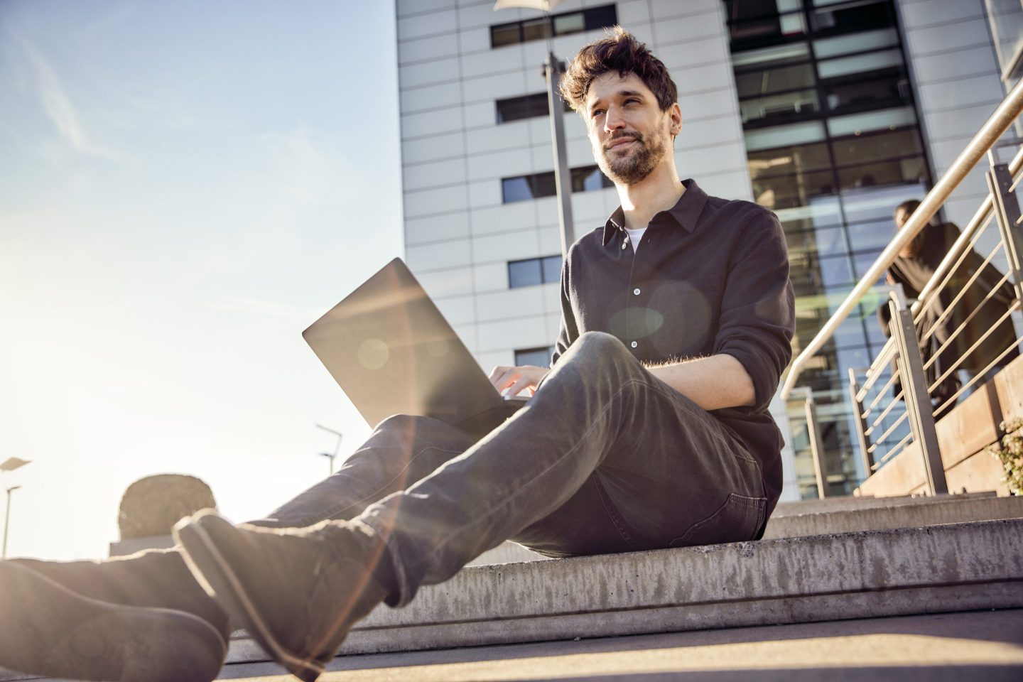 Entrepreneur using laptop while sitting on steps.