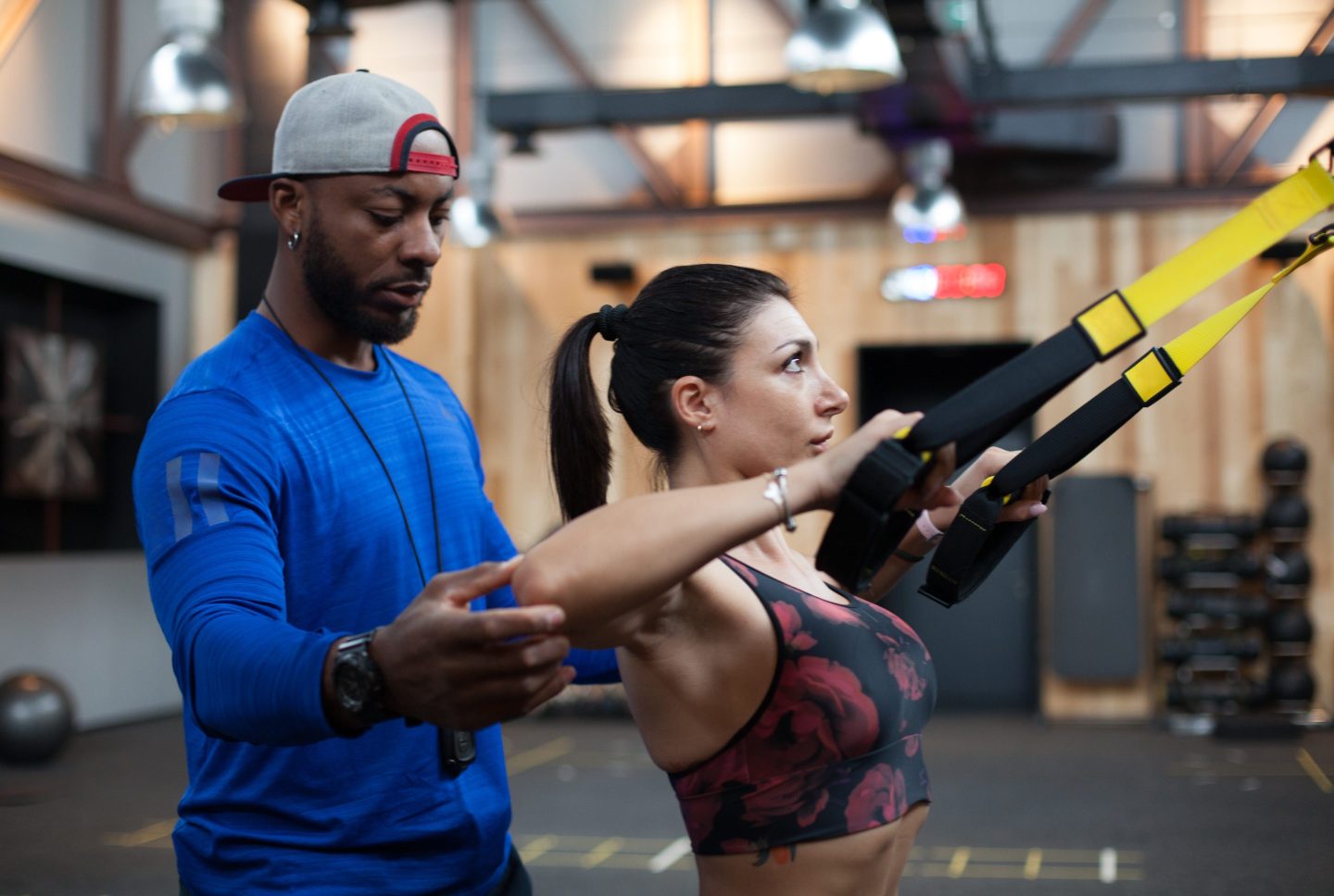 Fitness instructor assisting woman on exercise machine at the gym