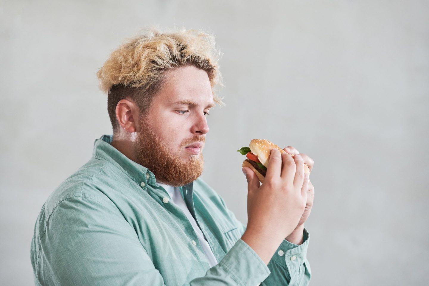 Man looks suspiciously at a burger he is holding