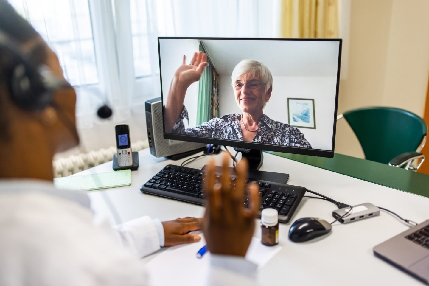 Female doctor a having a video call with a distant patient. General physician greeting patient during telemedicine appointment.