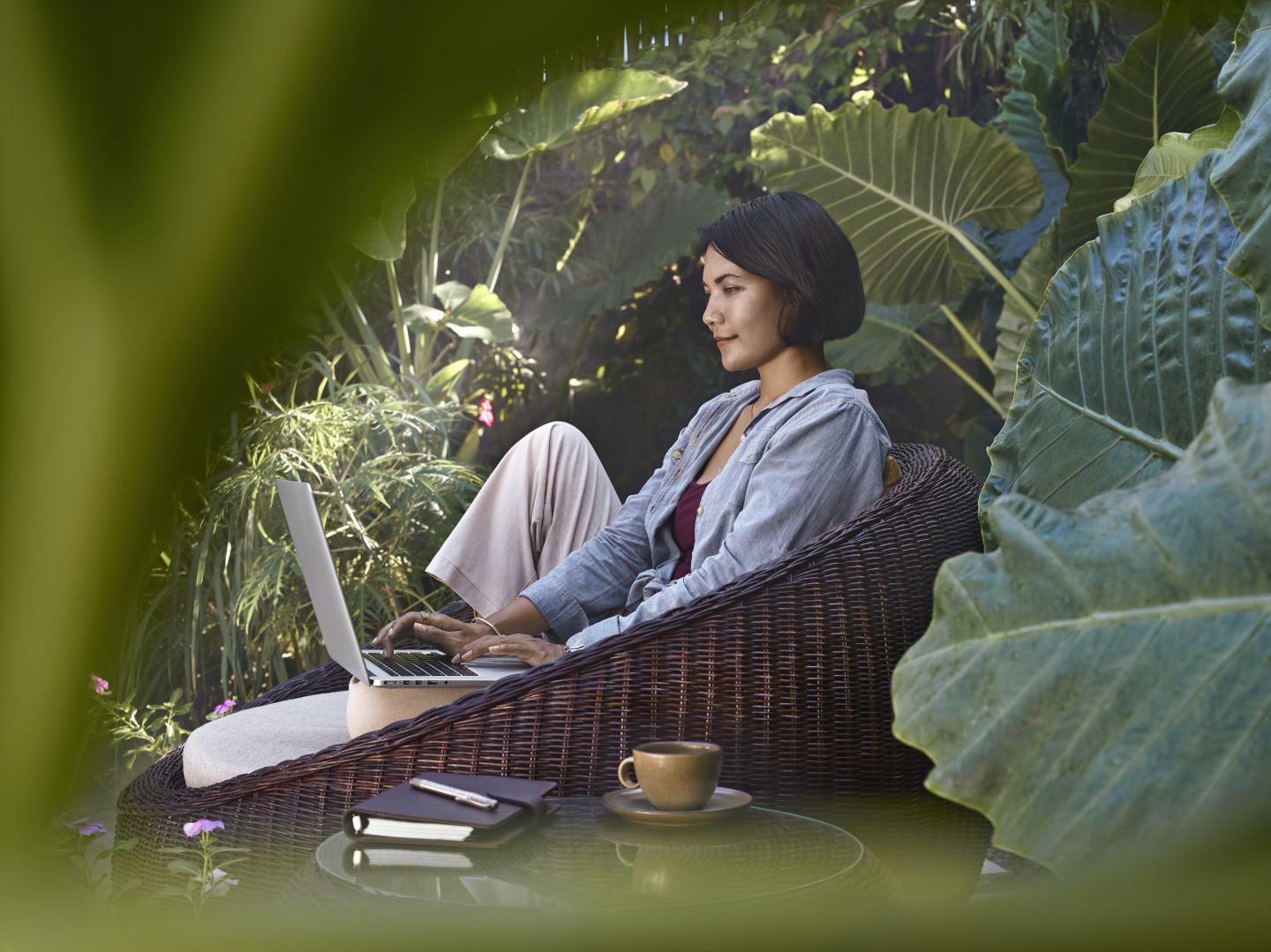 Woman working on her laptop in a lush garden