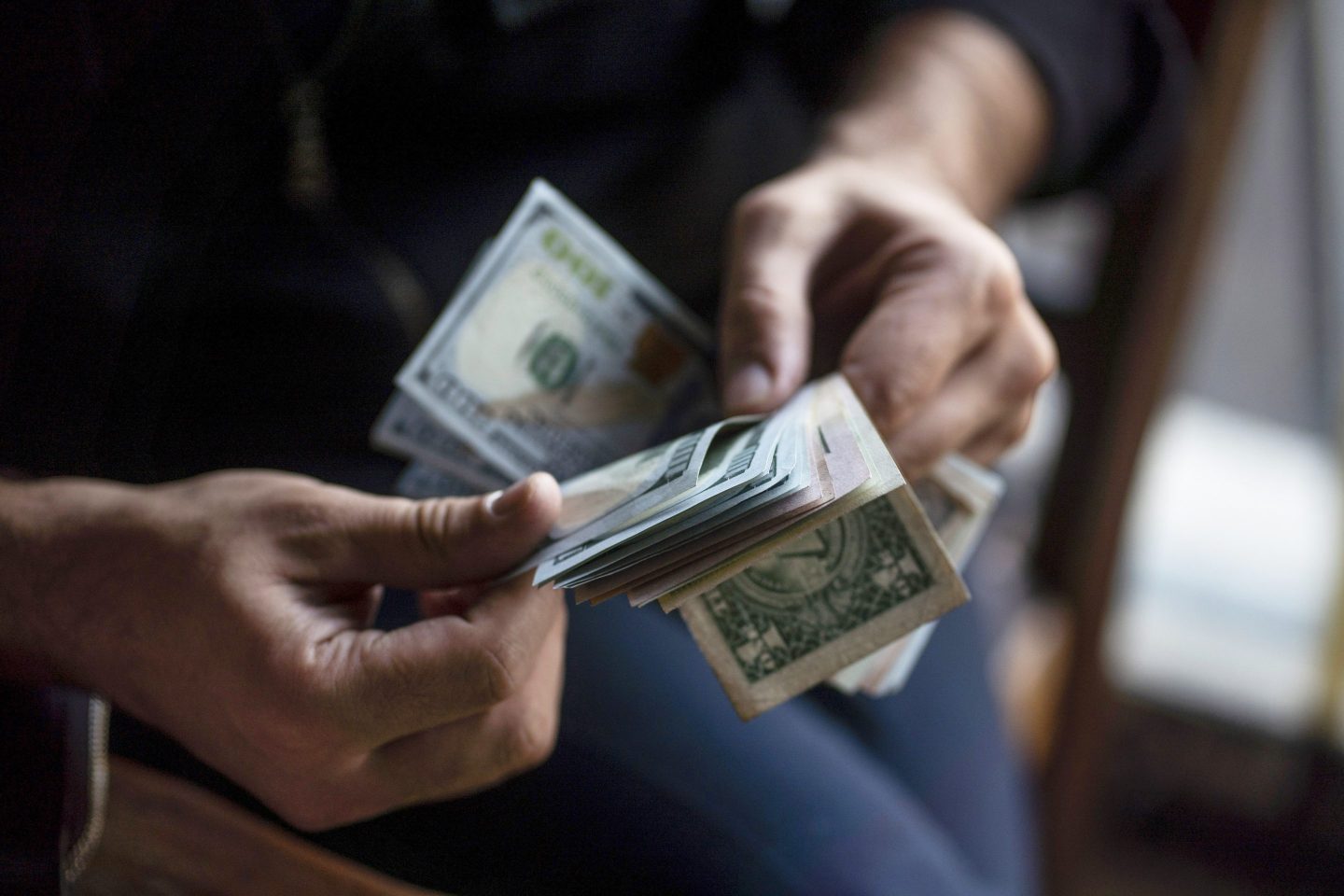 A Person Counting US Dollar Bills