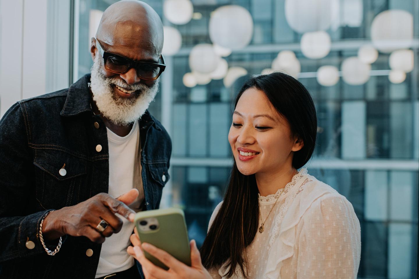 Close-up of a young woman showing an older man something on her smart phone
