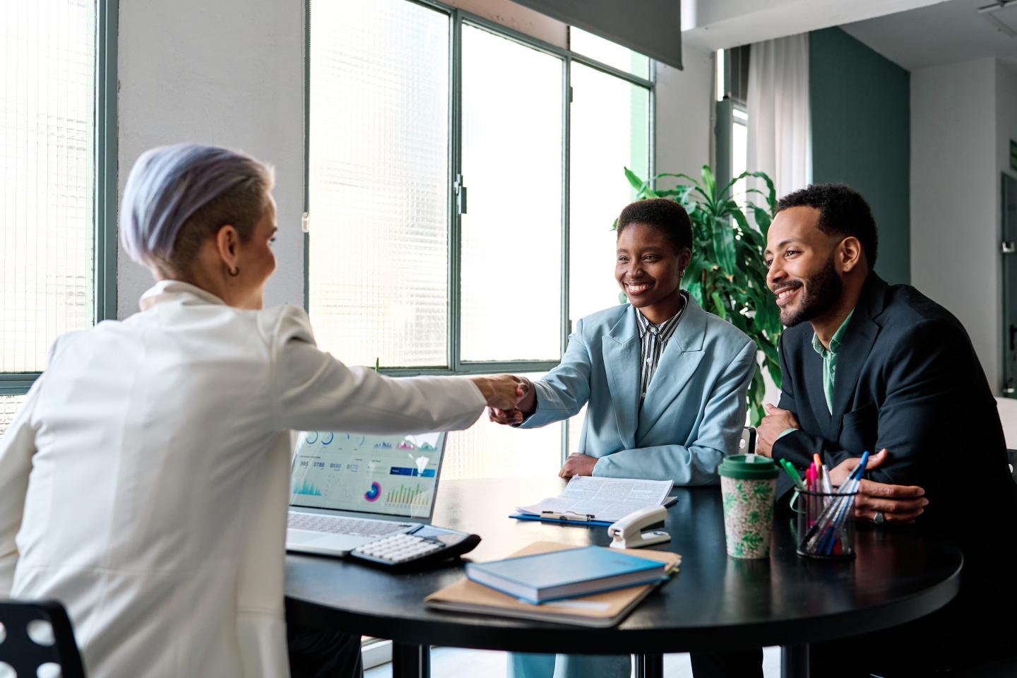 Businesswoman shaking hands with two other business people in the office