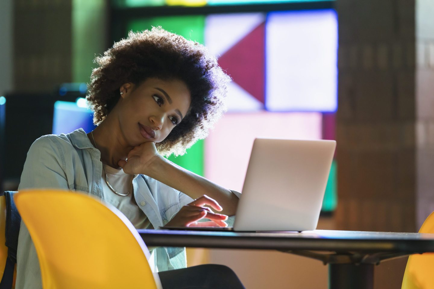 A young woman sits at a table, using a laptop.