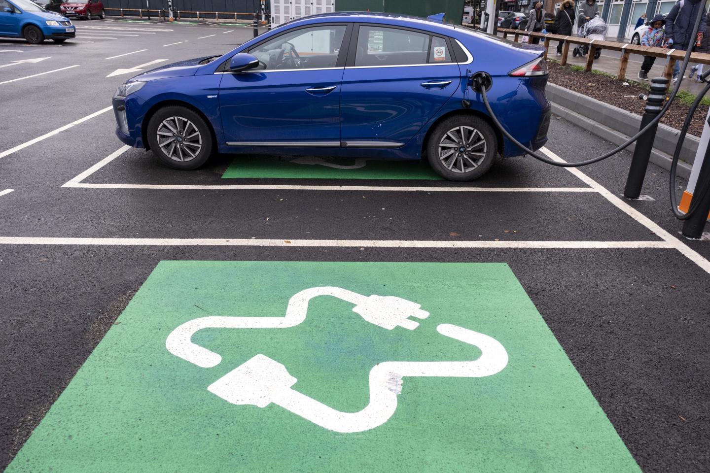 An electric vehicle shown charging in a car parking spot