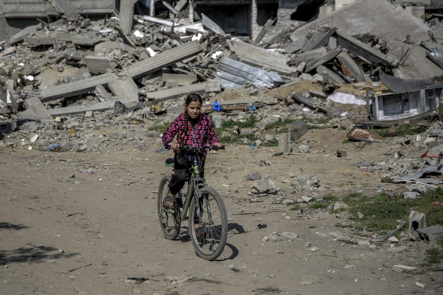 A Palestinian girl rides a bicycle past debris on Monday in Beit Lahia in the northern Gaza Strip.