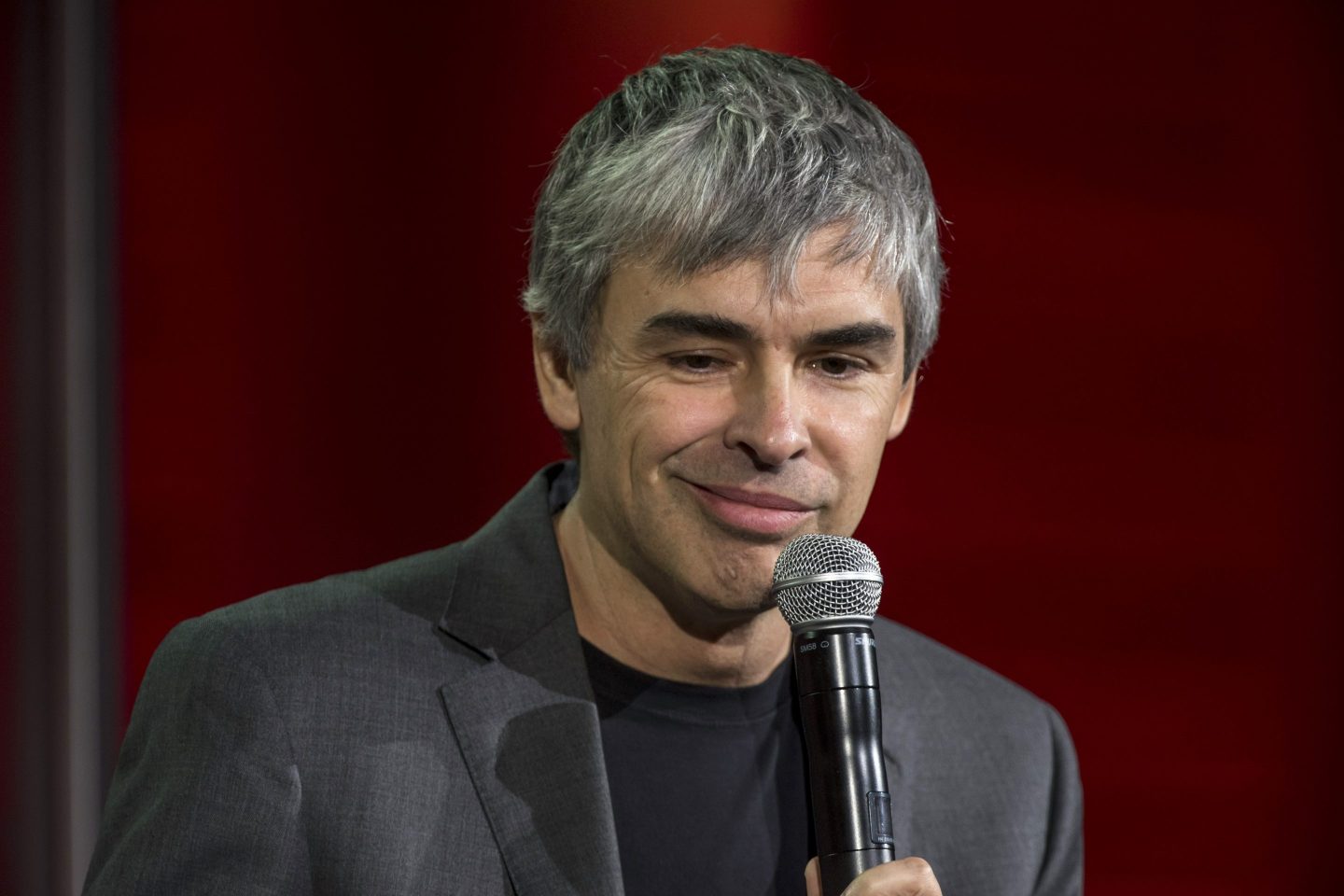 Google cofounder Larry Page holds a mic while smirking