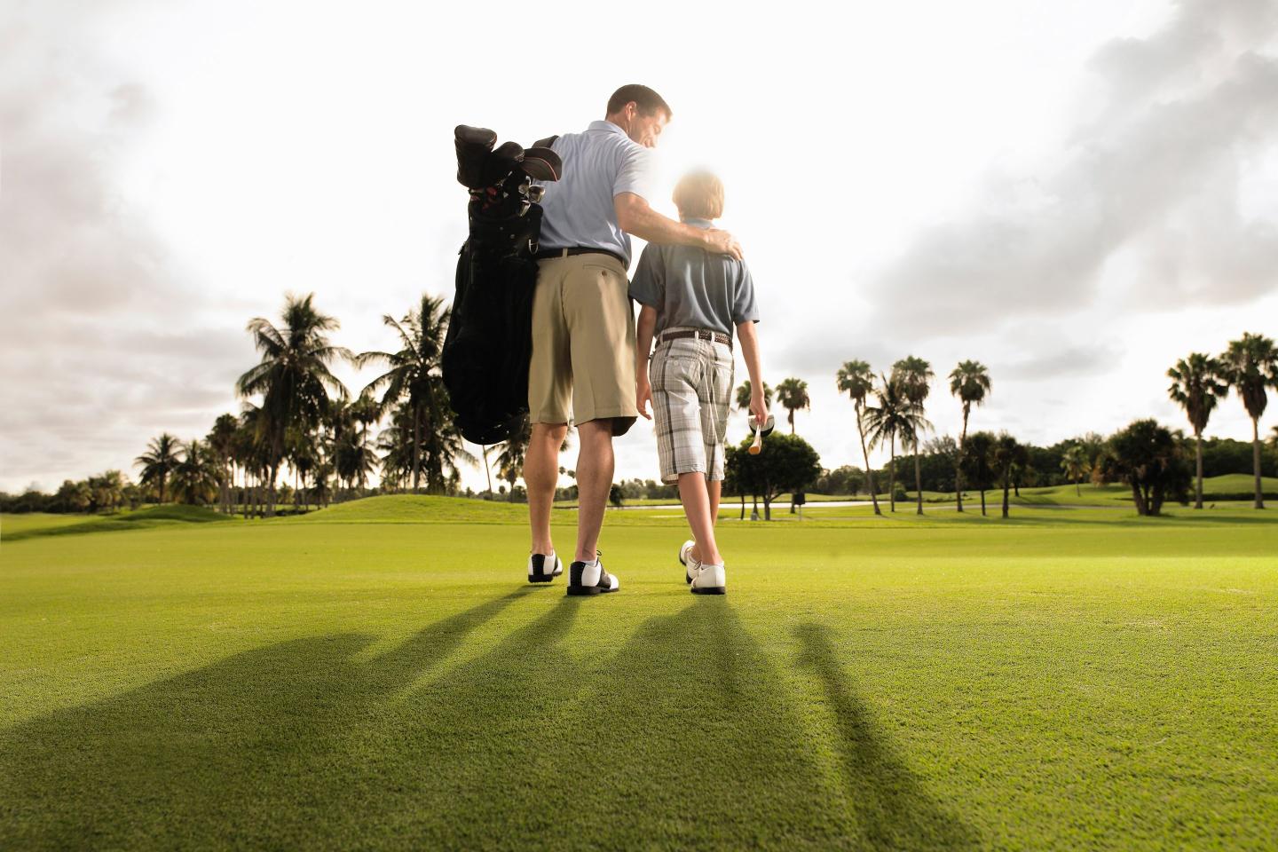 Father and son playing golf in early morning light