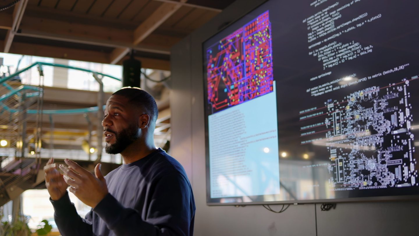 Man conducts a seminar with programming languages visible on the screen behind him