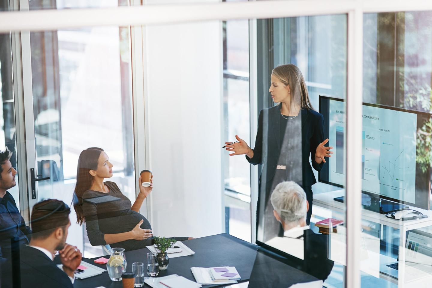 Woman gives a data presentation in a boardroom.