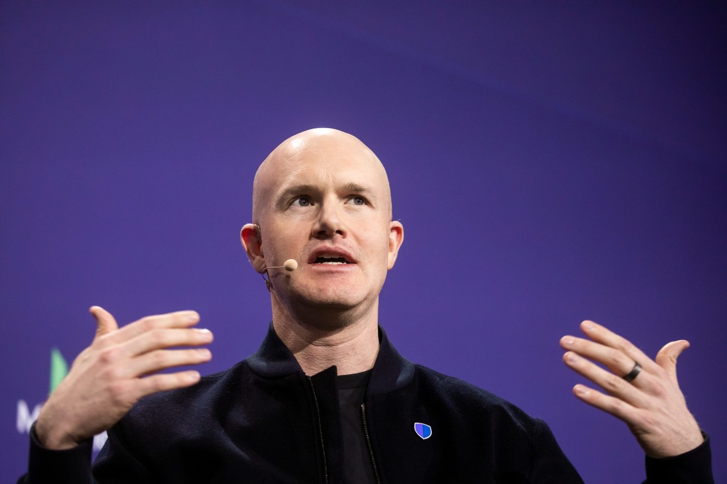 Coinbase CEO Brian Armstrong in front of a purple background and wearing a black shirt.