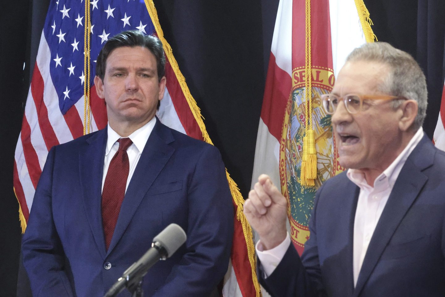 Florida Gov. Ron DeSantis listens to Central Florida Tourism Oversight District board chairman Martin Garcia, right, deliver remarks during a news conference at CFTOD headquarters at Walt Disney World, in Lake Buena Vista, Fla., Feb. 22, 2024.
