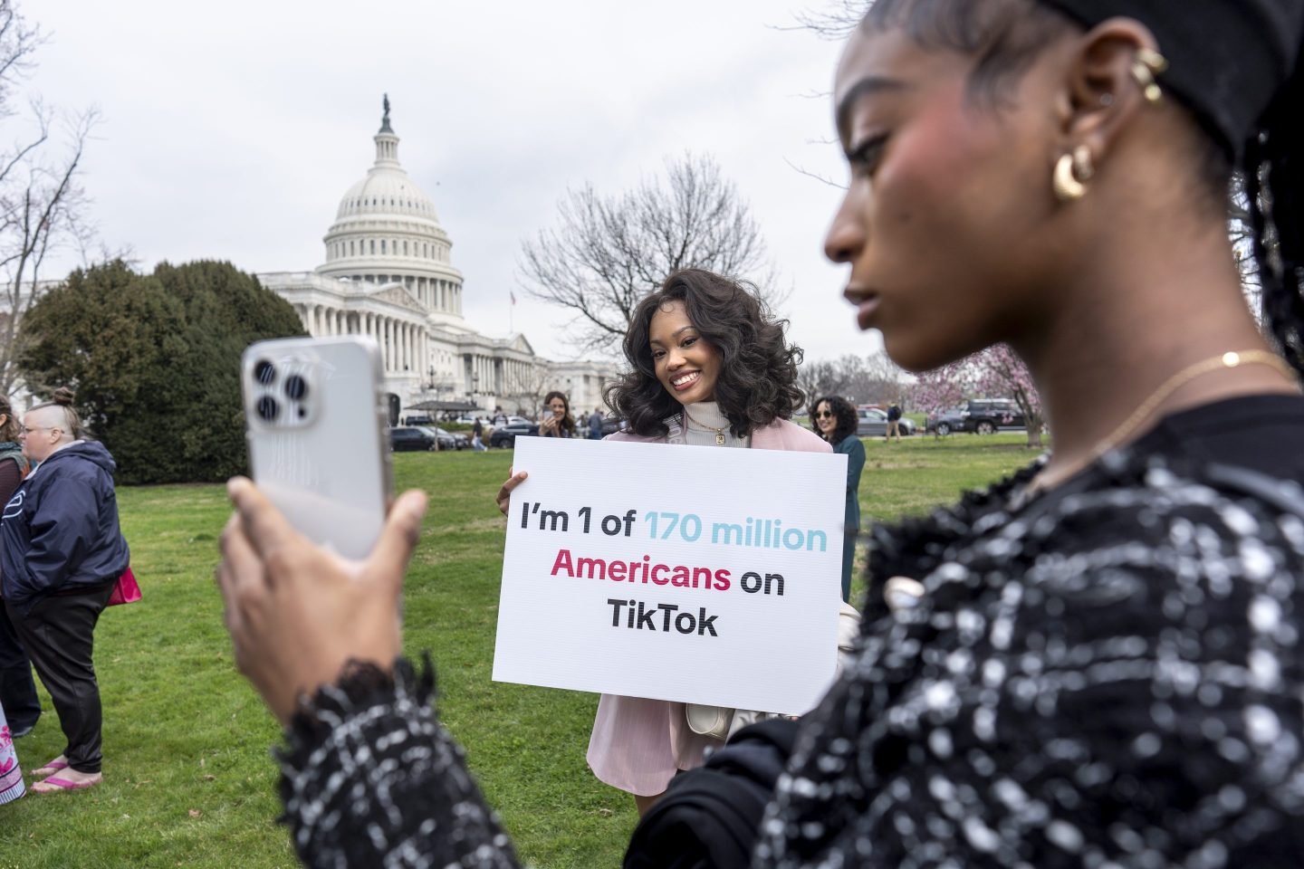 Devotees of TikTok, Mona Swain, center, and her sister, Rachel Swain, right, both of Atlanta, pose with a sign at the Capitol in Washington, March 13, 2024.