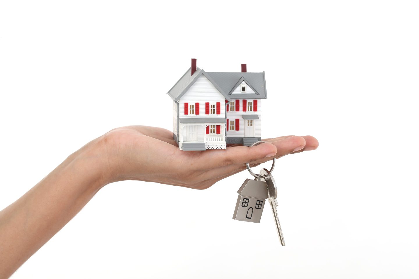 Photo of a woman's hand holding a small model of a home with keys