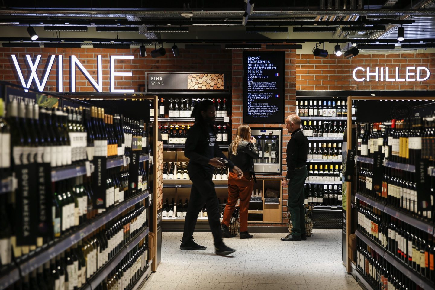 A customer, center, tastes a sample of wine in the wine and spirits section of the newly refurbished Marks & Spencer Group Plc Food shop in London, U.K,